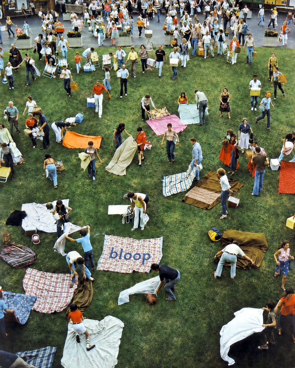 Un prato visto dall'alto, pieno di teli da picnic e di persone, con un telo Bloop al centro